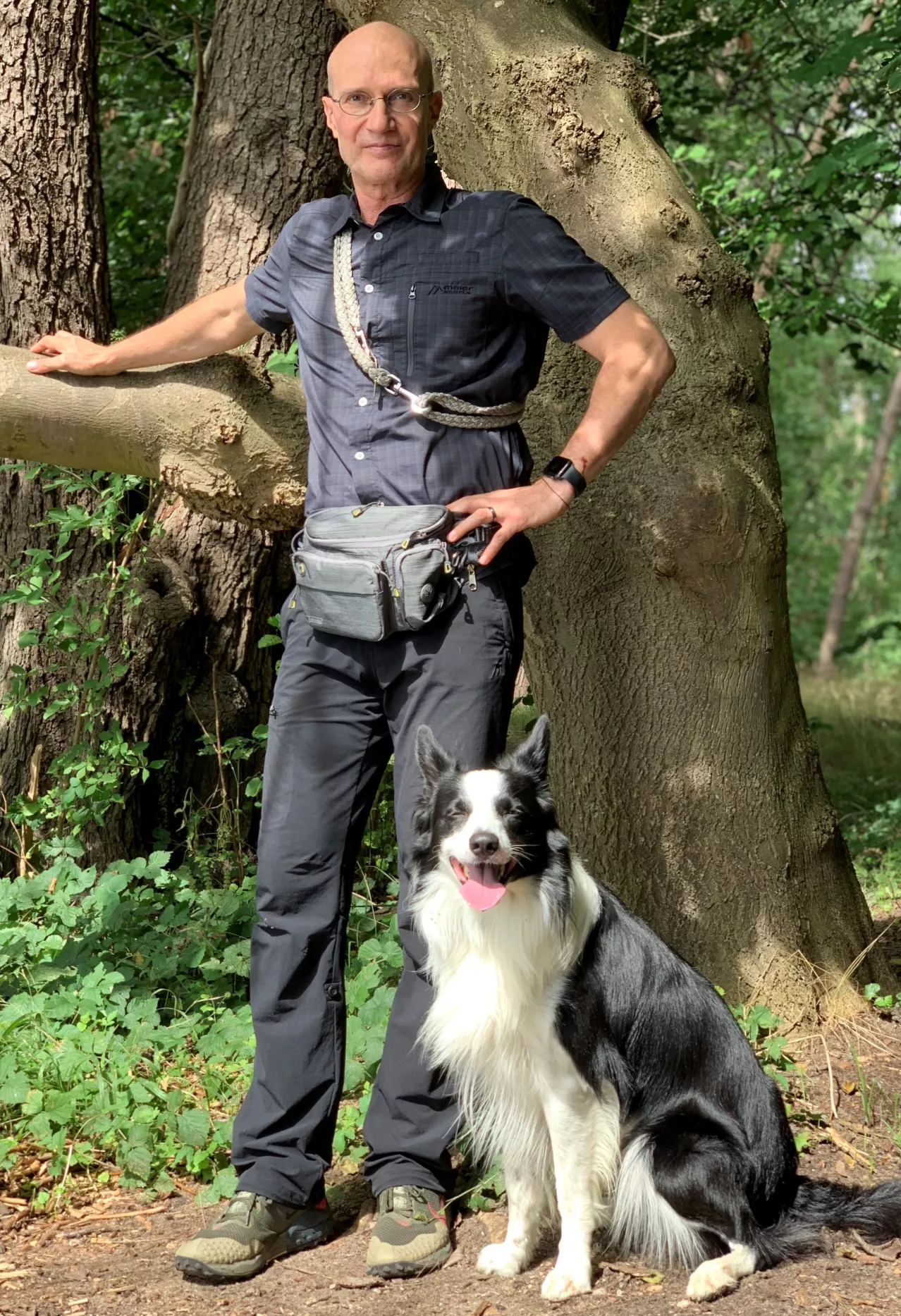 Webdesigner Lutz Thiel steht in voller Gestalt mit seinem Hund Eiko in der Naturlandschaft der Mecklenburgischen Seenplatte